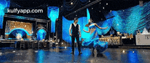 a man and a woman are dancing on a stage and the website kulfyapp.com is visible in the corner