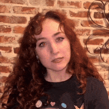 a woman with red curly hair is wearing a black shirt with hearts on it