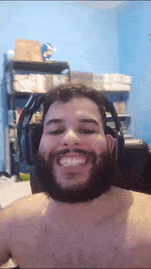 a shirtless man with a beard wearing headphones and smiling .