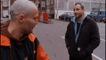 two men are standing in a parking lot and one has a tattoo on his head that says t.