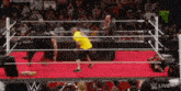 a man in a yellow shirt is wrestling in a ring .
