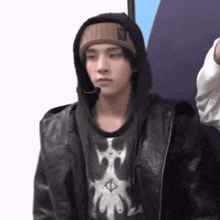 a man wearing a hooded jacket and a beanie looks at the camera