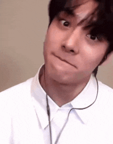 a man wearing headphones and a white shirt is making a face .