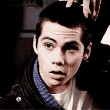 a close up of a young man 's face with a hand holding his head