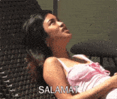 a woman in a pink tank top is laying on a chair with the word salamat written above her