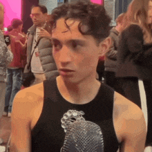 a man wearing a black tank top with a picture of a bird on it