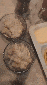 three bowls of food are sitting on a table with a plate of food in the background .