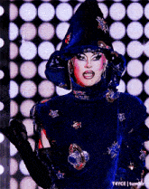 a drag queen is wearing a blue costume with stars on it and a hat