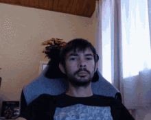 a man with a beard is sitting in a chair wearing a t-shirt that says ' i love you '