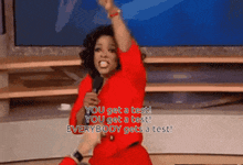 a woman in a red shirt is holding a microphone and saying you get a test you get a test