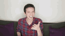 a man in a plaid shirt is sitting on a couch