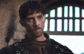a man with a beard is standing in front of a window with bars and the words load all gifs on the bottom