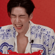 a man wearing a blue and white floral shirt is laughing