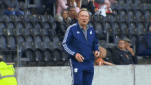a man wearing a blue adidas jacket with the letter s on the front