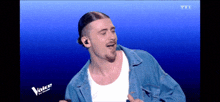 a man singing on a stage with the word voice on the bottom right corner