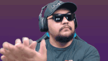 a man wearing headphones and sunglasses has the letter l on his hat