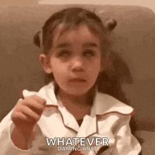 a little girl is sitting on a couch and says whatever
