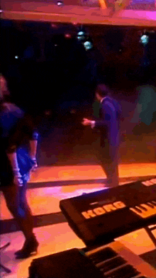 a korg keyboard sits on a stage in front of a group of people