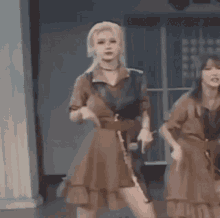 two women in brown dresses are standing next to each other on a stage holding microphones .