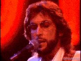 a close up of a man singing into a microphone with gifrun.com in the corner