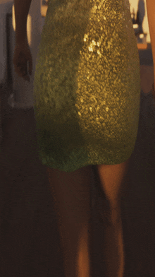 a woman in a green sequined dress is walking on a wooden floor