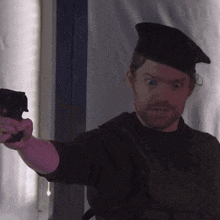 a man in a beret is pointing a gun