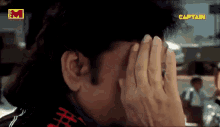 a close up of a person covering their face with their hands with a captain logo in the corner