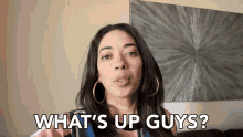 a woman says " what 's up guys " in front of a wall