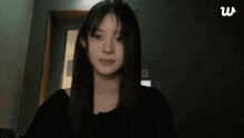 a woman with long hair is making a funny face and waving her hand .