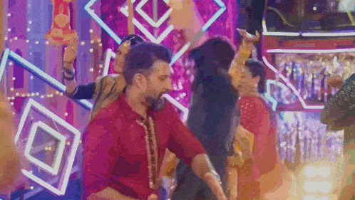 a man in a red shirt is dancing on a stage in front of a crowd of people .