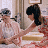 two women are sitting on a bed looking at a picture