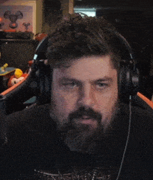 a man with a beard is wearing headphones and making a funny face .