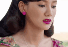 a woman wearing pink earrings and a floral dress