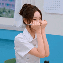 a woman covering her face with her hands with a calendar behind her