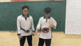 two young men are standing in front of a blackboard .