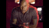 a man is sitting at a bar holding a plastic cup with a red liquid in it .