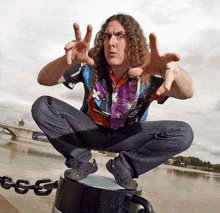 a man with long curly hair squatting on a fence post