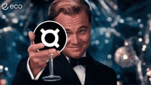 a man in a tuxedo is holding a wine glass in front of a circle with the letter q on it
