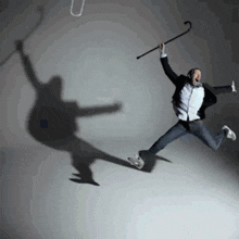 a man jumping in the air with a cane in his hand