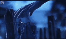 a close up of a person 's hand touching a fence post in the dark
