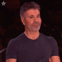 a man in a black shirt is making a face with his hands in the air