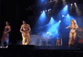 three people are dancing on a stage with blue lights