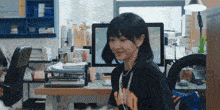 a woman wearing a t-shirt that says ' tokyo ' on it is sitting at a desk