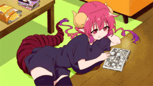 a girl with horns is laying on the floor reading a magazine