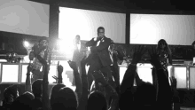 a man singing into a microphone in front of a crowd with their hands in the air