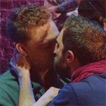 a man with a beard is kissing another man