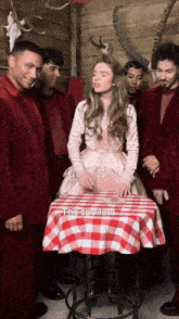 a group of people are standing around a table with a red and white checkered tablecloth that says " the spoilers "