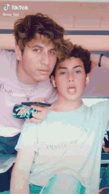 two young men are posing for a picture and one of them is holding a can of mountain dew