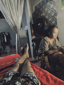 a man laying on a bed with a woman sitting behind him