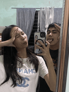 a man and a woman are taking a selfie in a mirror